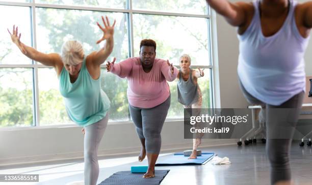 four women taking yoga class, in warrior 3 pose - on one leg stock pictures, royalty-free photos & images