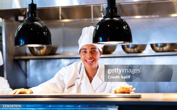 woman working as chef in commercial kitchen, smiling - catering occupation stock pictures, royalty-free photos & images