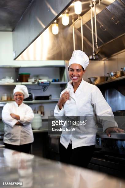 two women working as chefs in restaurant kitchen - chefs hat stock pictures, royalty-free photos & images