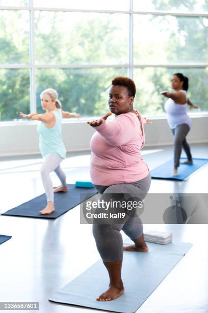 drei frauen, die yoga-kurs nehmen, in krieger 2 pose - 3 gym stock-fotos und bilder