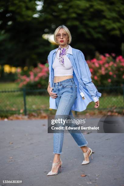 Emy venturini wears brown sunglasses from Prada, gold large earrings, a white with purple flower print pattern Gucci scarf, a gold long chain...