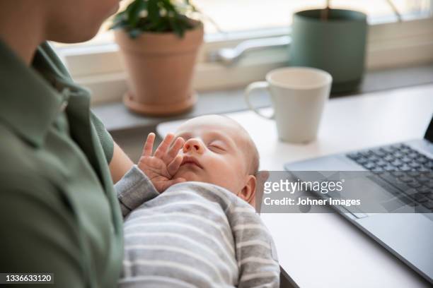 father holding baby son and working from home - genderblend stock-fotos und bilder