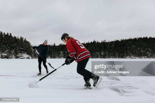 men ice-skating on frozen lake - outdoor ice hockey stock pictures, royalty-free photos & images