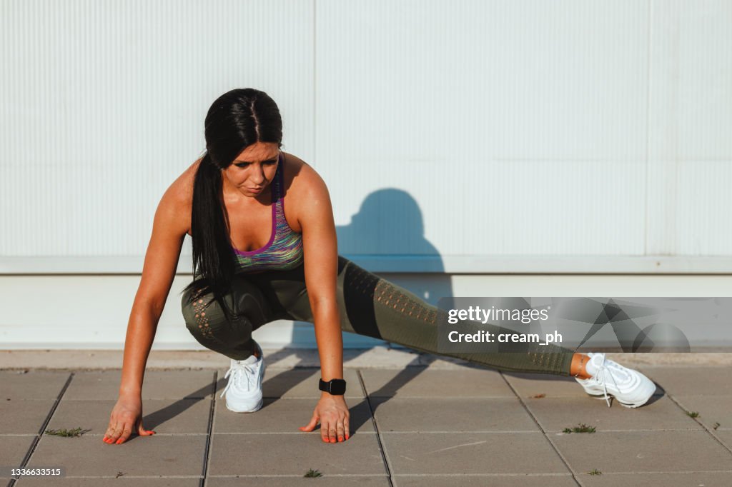 Woman lunging and stretching in the city public park