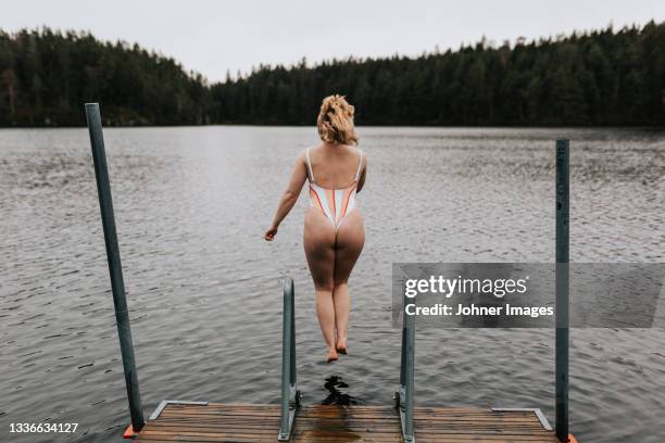 rear view of woman jumping into lake - long jetty stock pictures, royalty-free photos & images