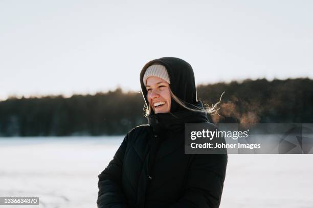 woman standing on frozen lake - women winter snow stock-fotos und bilder