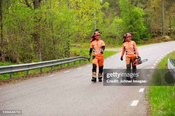 female lumberjacks walking on forest road - holzfäller stock-fotos und bilder