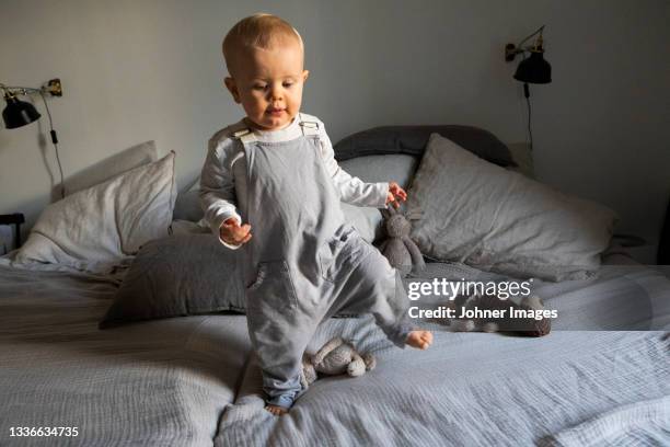 baby boy walking on bed - king size bed stockfoto's en -beelden