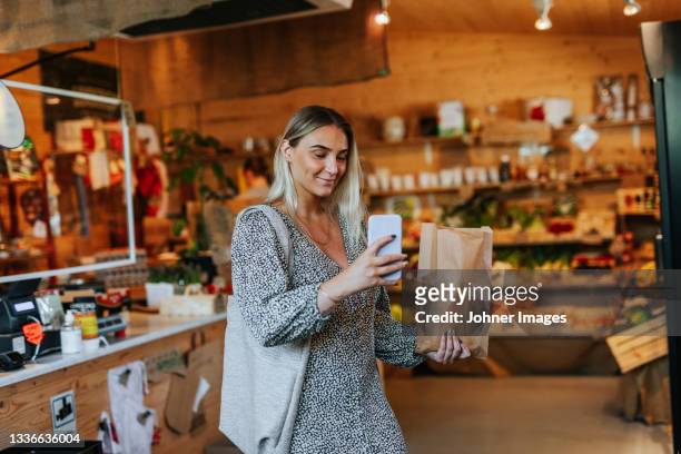 smiling woman in shop taking picture - johner images bildbanksfoton och bilder