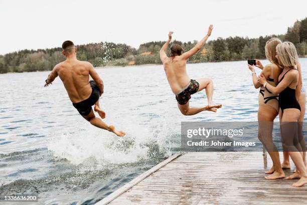 people jumping into lake from jetty - een bad nemen stockfoto's en -beelden