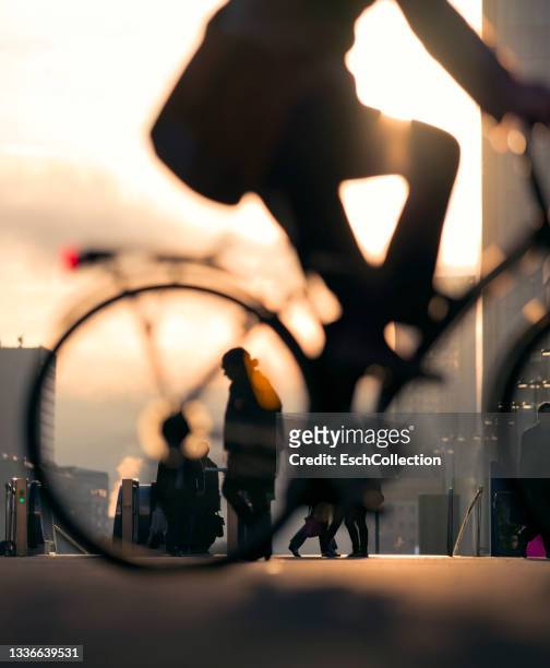 businessman on bicycle passing skyline of business district at dawn. - zonnig stockfoto's en -beelden