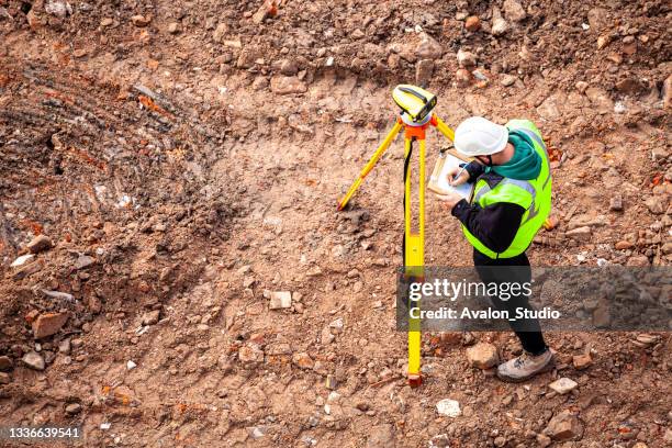 a surveyor on a construction site uses an optical level - geodetisk kupol bildbanksfoton och bilder