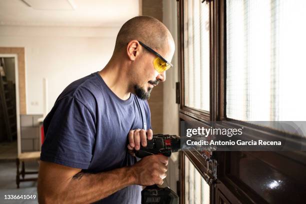 locksmith changes a lock at home with a battery drill - serralheiro imagens e fotografias de stock
