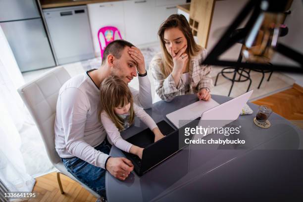 man and woman working on laptops in home office while her daughter distraught - mom head in hands stock pictures, royalty-free photos & images