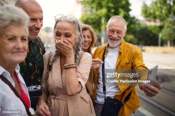 group of happy senior friends tourists on a walk in city, taking selfie. - city 70's stock pictures, royalty-free photos & images