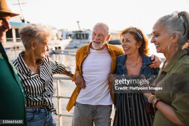 group of happy senior friends tourists standing in city port, talking. - uomo anziano felice foto e immagini stock