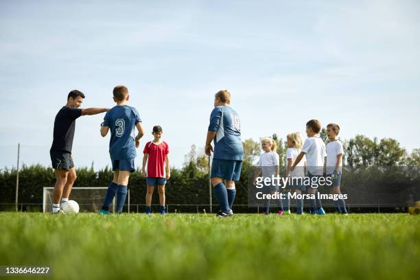 low angle view of coach teaching soccer to kids at field - practicing stock pictures, royalty-free photos & images