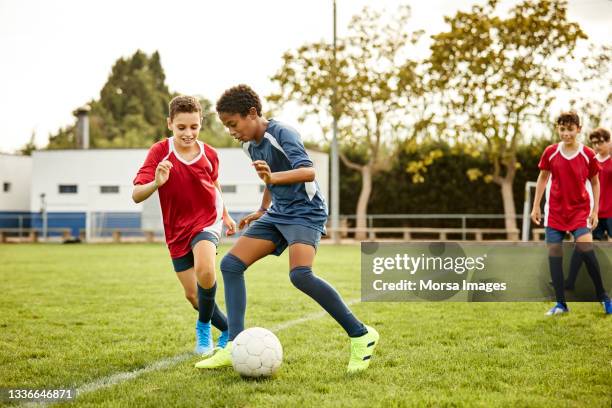 adolescentes practicando fútbol en campo deportivo - partido de fútbol fotografías e imágenes de stock