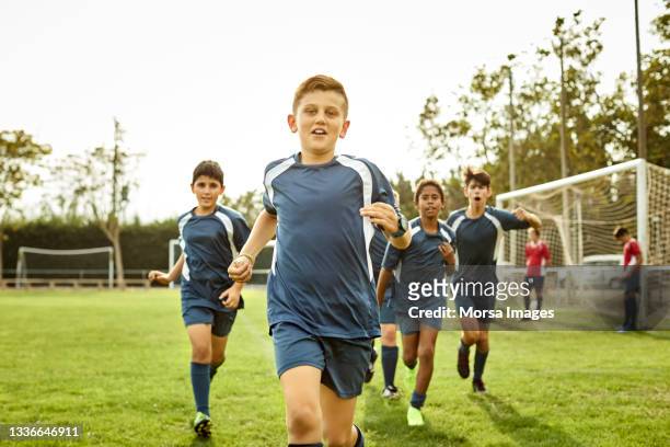 porträt von teenagern, die auf dem fußballplatz laufen - football training stock-fotos und bilder