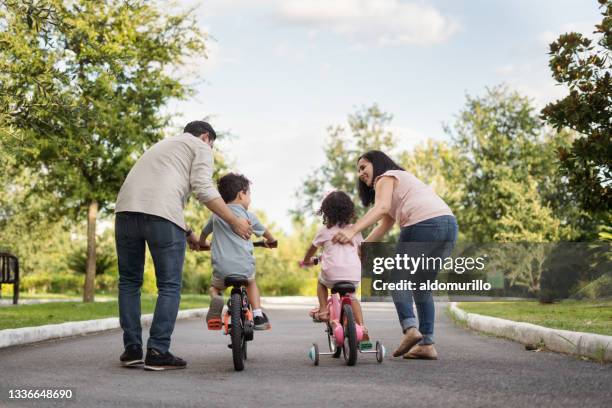 parents teaching their little child to ride a bike - public park kids stock pictures, royalty-free photos & images