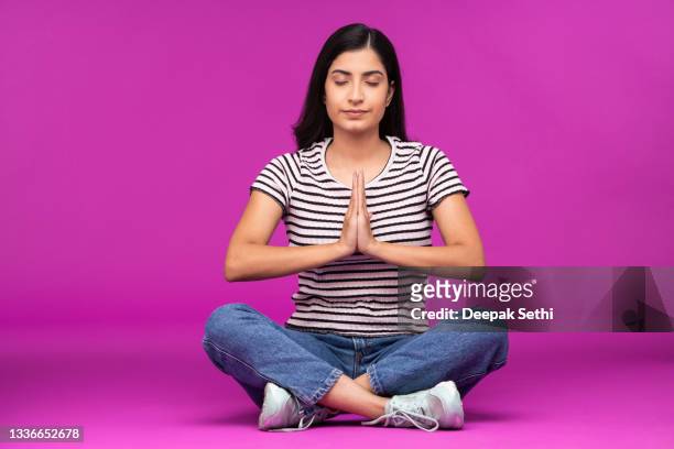 young woman on purple background - fashion woman floor cross legged stock pictures, royalty-free photos & images