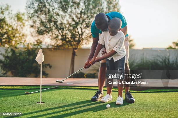 full length shot of a handsome young man and his son playing golf in their backyard - golf player stockfoto's en -beelden