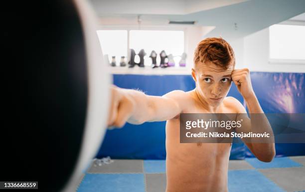 boxer is exercising with a punching bag - teen martial arts stock pictures, royalty-free photos & images