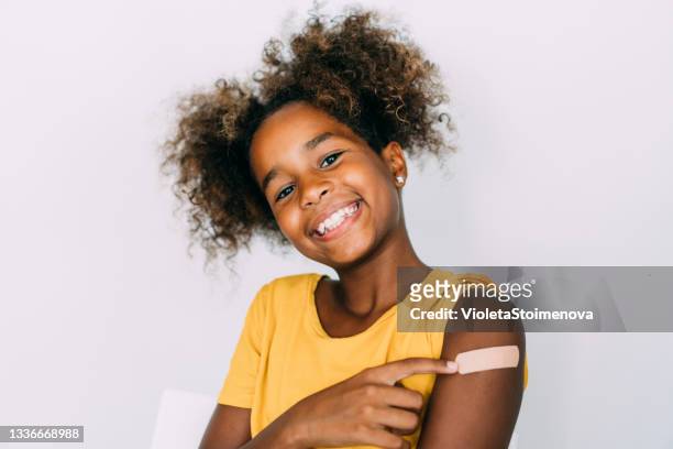 little girl showing her arm after getting vaccinated. - child vaccine stock pictures, royalty-free photos & images