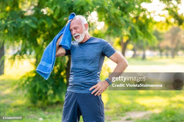 uomo anziano che si prende una pausa dopo l'esercizio nel parco. - caldo foto e immagini stock