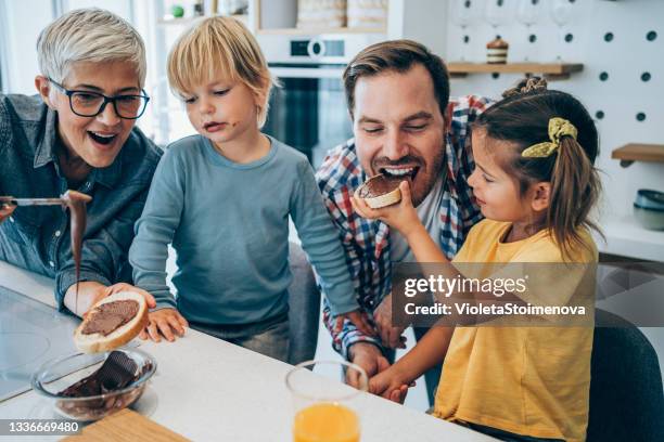 glückliche familie beim frühstücken. - biting into chocolate stock-fotos und bilder