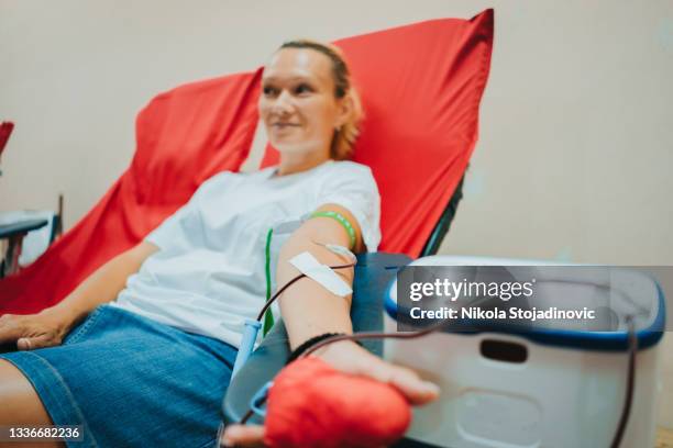 une jeune femme caucasienne avec un cœur de jouet à la main donne du sang - nursing slogans photos et images de collection