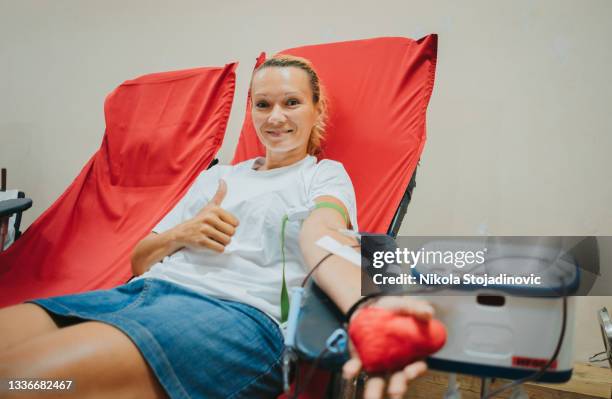 junge kaukasische frau mit spielzeugherz in der hand spendet blut - donate stock-fotos und bilder