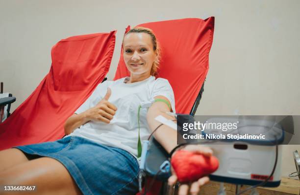 giovane donna caucasica con il cuore di toy in mano dona il sangue - sangue foto e immagini stock