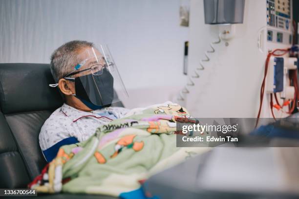 asiatischer chinesischer senior mann auf stuhl mit gesichtsschild, gesichtsmaske ruht unter dialysebehandlung im krankenhaus - dialysis stock-fotos und bilder