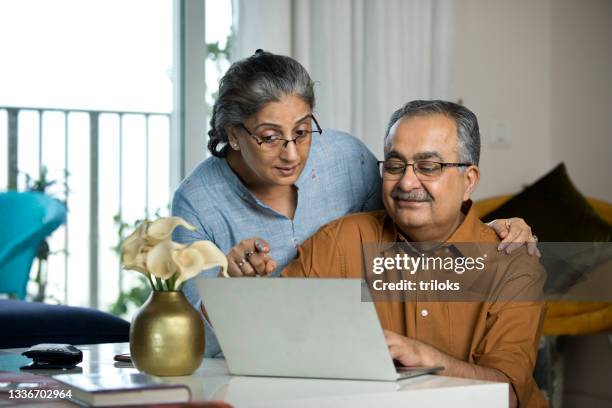 senior couple using laptop while working on home budget - indian old man stockfoto's en -beelden