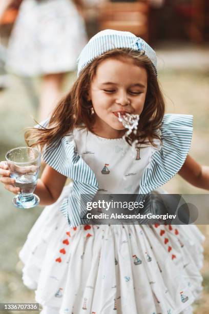 cute female child spitting and playing with water outside - spats stock pictures, royalty-free photos & images