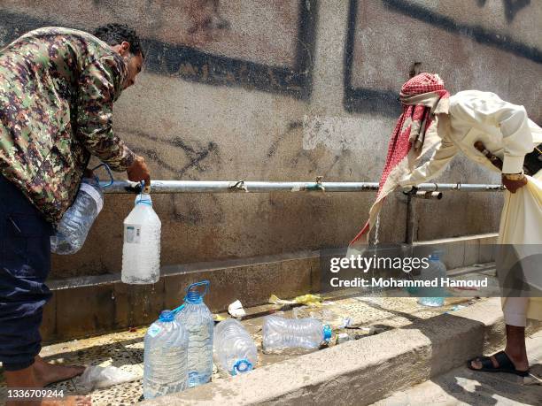 Yemeni boys collect clean water provided by a charitable group amid a severe water crisis on August 27, 2021 in Sana'a, Yemen. In war-torn Yemen, the...