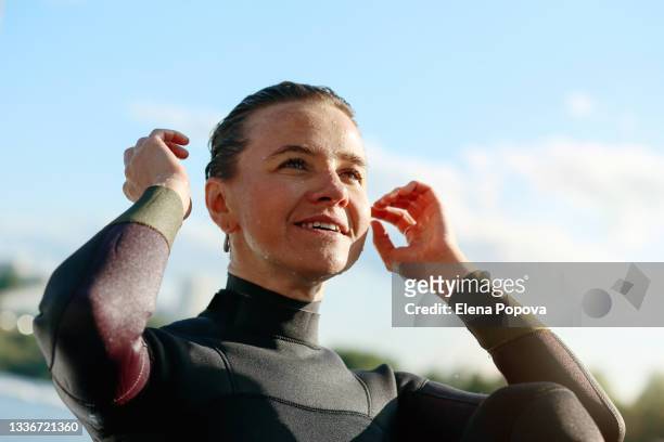 portrait of young adult woman surfer against blue sky - action face stock pictures, royalty-free photos & images