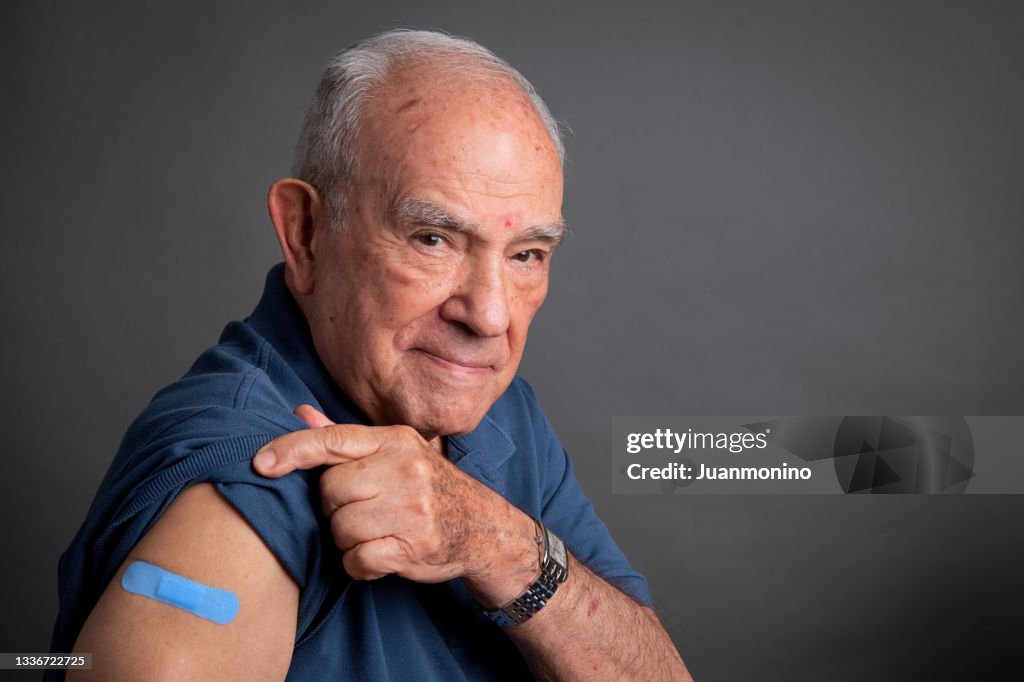 Senior man posing showing his vaccination band-aid in his arm