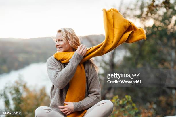 smiling woman looking away wearing scarf during autumn - shawl stock-fotos und bilder
