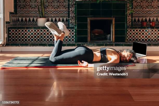 tired young woman lying on exercise mat during home workout - allongé sur le devant photos et images de collection