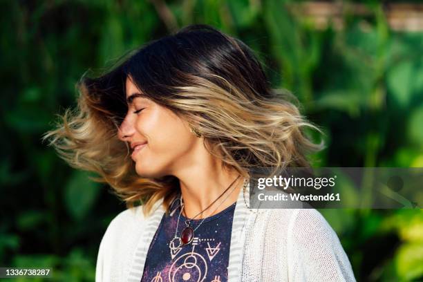 young woman smiling while tossing hair - haare schütteln stock-fotos und bilder
