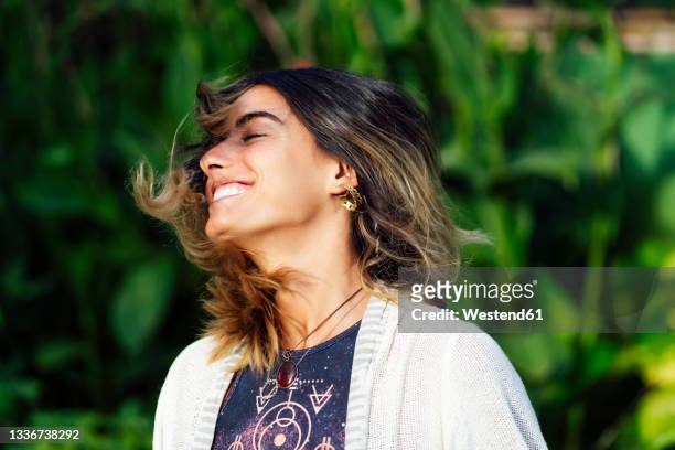 happy woman with eyes closed while tossing hair - hair toss stockfoto's en -beelden
