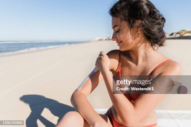 woman applying sunscreen at beach on sunny day - 防曬油 個照片及圖片檔