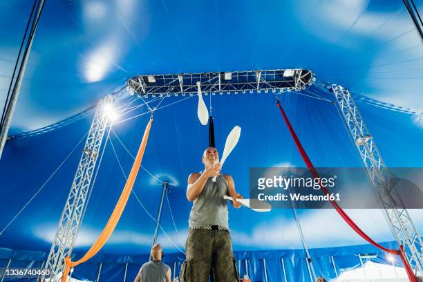 male athlete with juggling pins practicing at circus - zirkuszelt stock-fotos und bilder