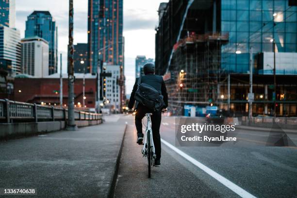 bike riding urban commuter at dusk - seattle people stock pictures, royalty-free photos & images