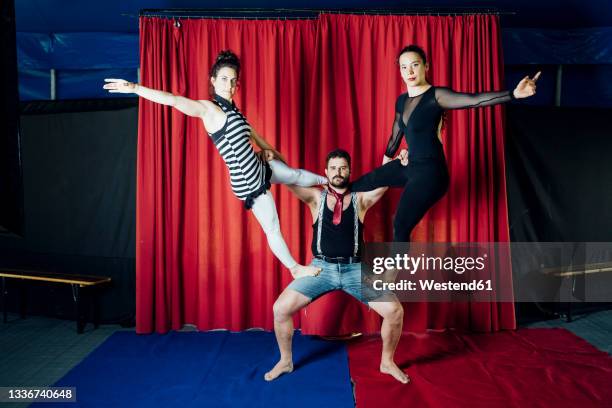 female performer stretching while standing on male acrobat at circus - circus curtains stock pictures, royalty-free photos & images