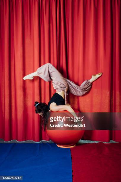female circus performer balancing on red ball - acrobatic activity photos et images de collection