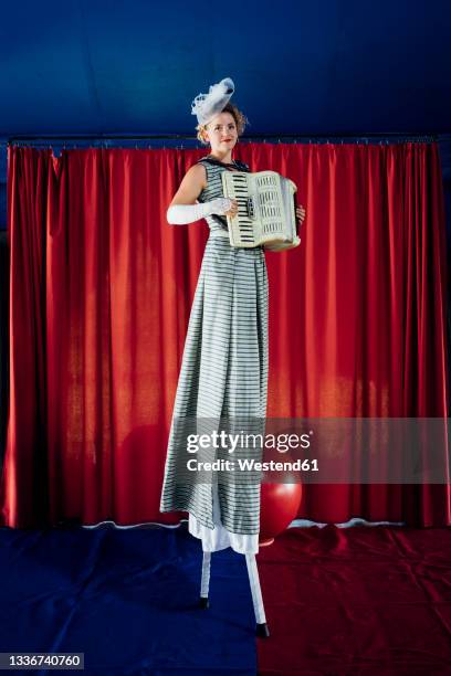 female artist playing accordion while walking with stilts on stage - styltor bildbanksfoton och bilder