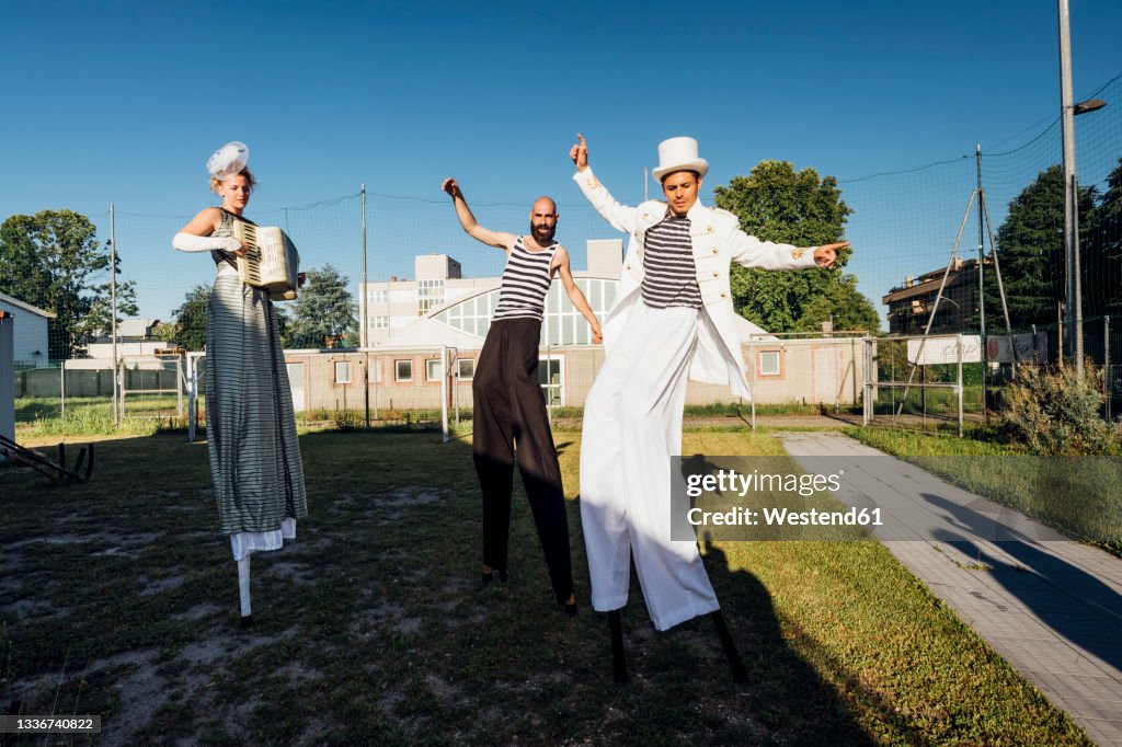 Male and female artists dancing while standing on stilts